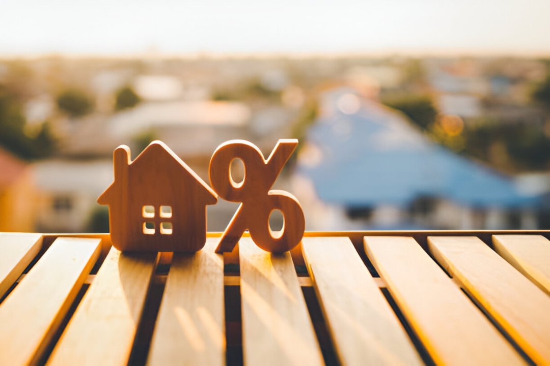A small wooden house and a percentage sign sit on a wooden table, representing the path to Buy a house without a mortgage from KBR Investing. A small wooden house and a percentage sign sit on a wooden table, representing the path to Buy a house without a mortgage from KBR Investing.
