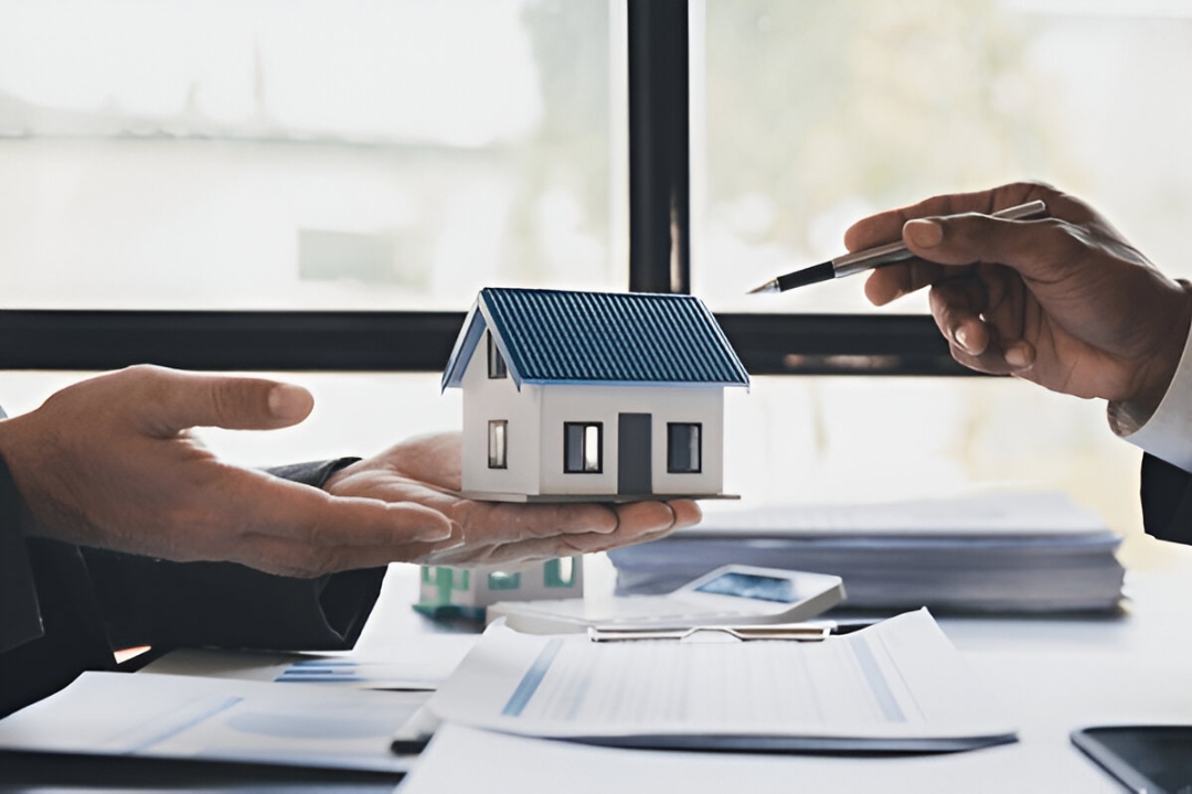  A close-up of a person's hands shows a small house model and a pen, offering Mortgage alternatives for penalty box buyers with KBR investing.