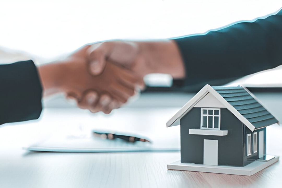  Handshake over a contract and house model, symbolizing KBR investing's assistance in Qualifying for owner financing loans.