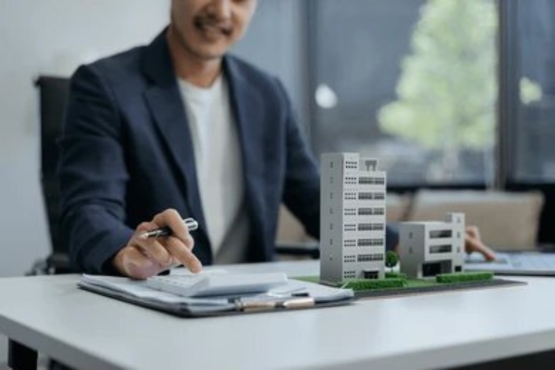  A man with a calculator and house model demonstrates Kbr investing's solutions for Home buying options for penalty box buyers.
