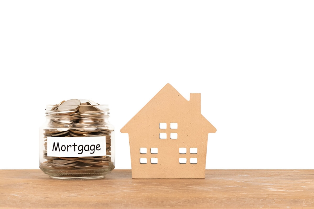  A small wooden house sits next to a jar of coins labeled "Mortgage", representing Kbr investing's solutions for Owner financing after bank rejection.