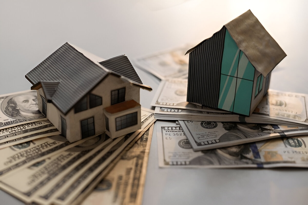Two model houses rest on piles of US dollar bills, representing information about a Work visa home loan from Kbr investing.