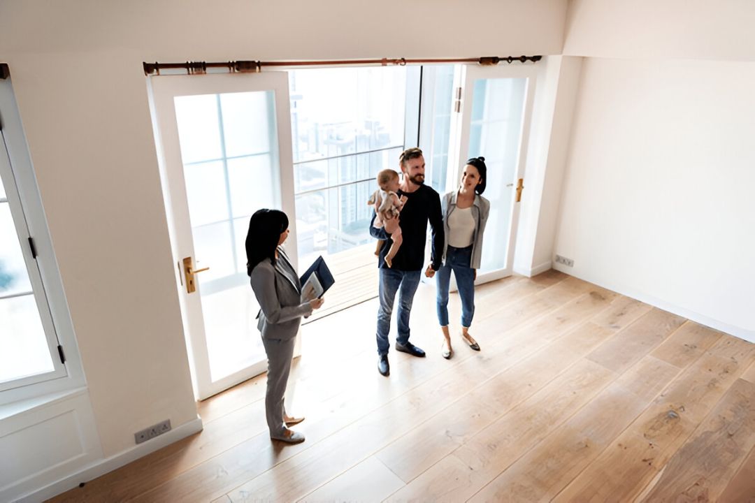 A family with a baby meets a real estate agent in a bright, empty room, representing Owner finance properties with no credit check options from KBR Investing.