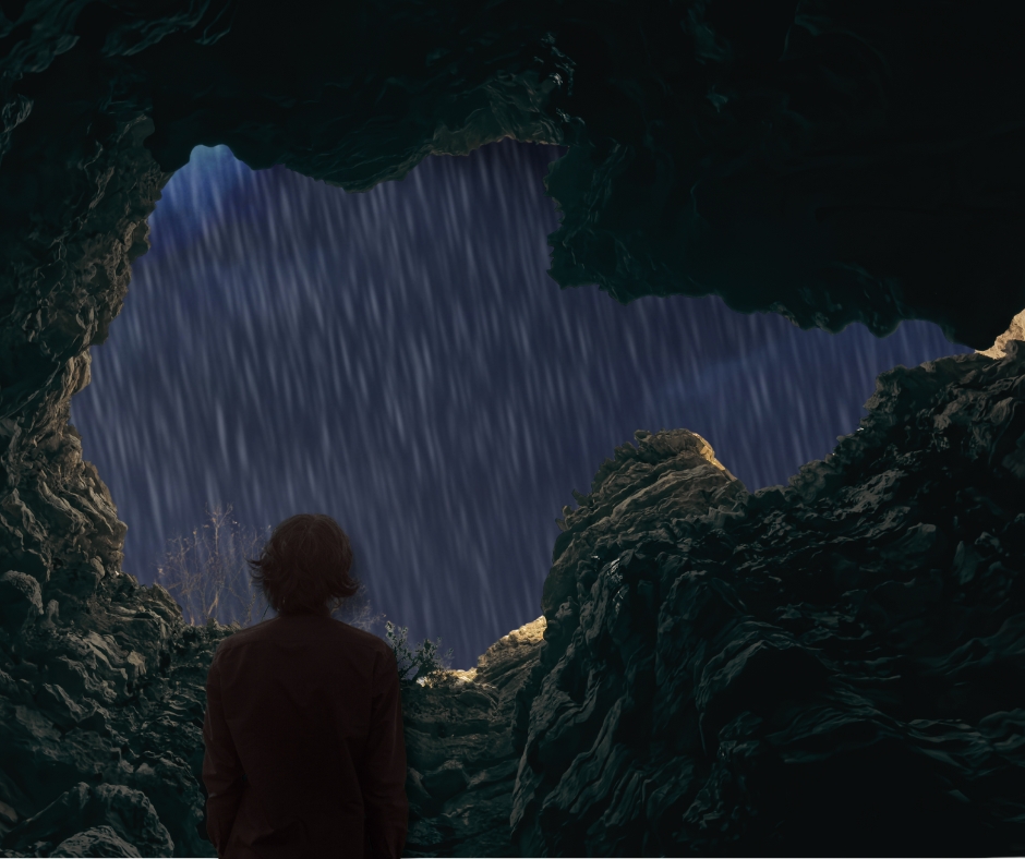 erson standing in a dark pit looking out at heavy rain from the cave opening