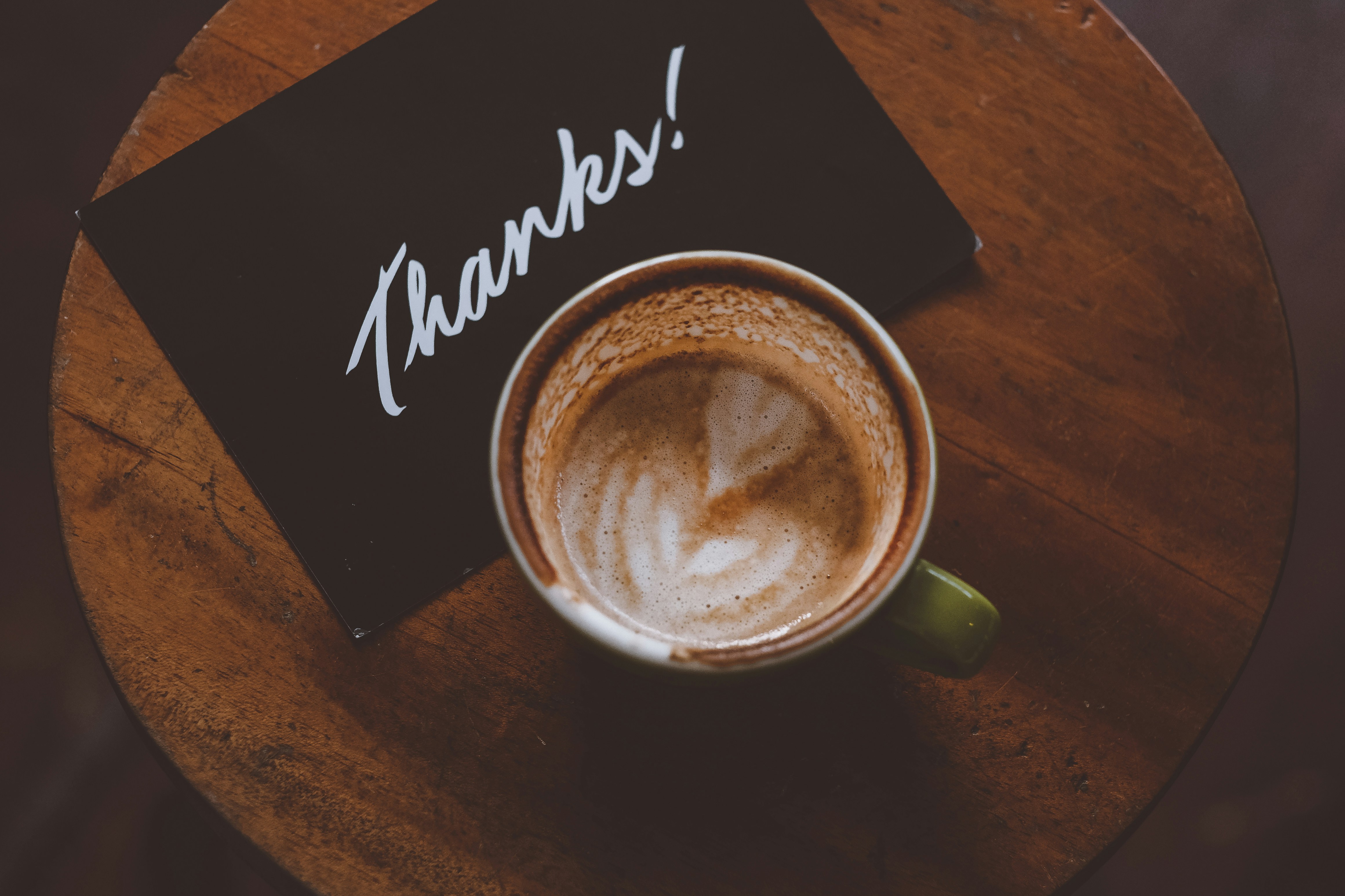 A cup of cappuccino with a note that says "thanks" A cup of cappuccino with a note that says "thanks"