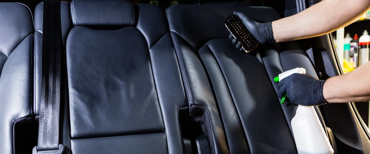 Detailing leather car seats with cleaning brush and spray