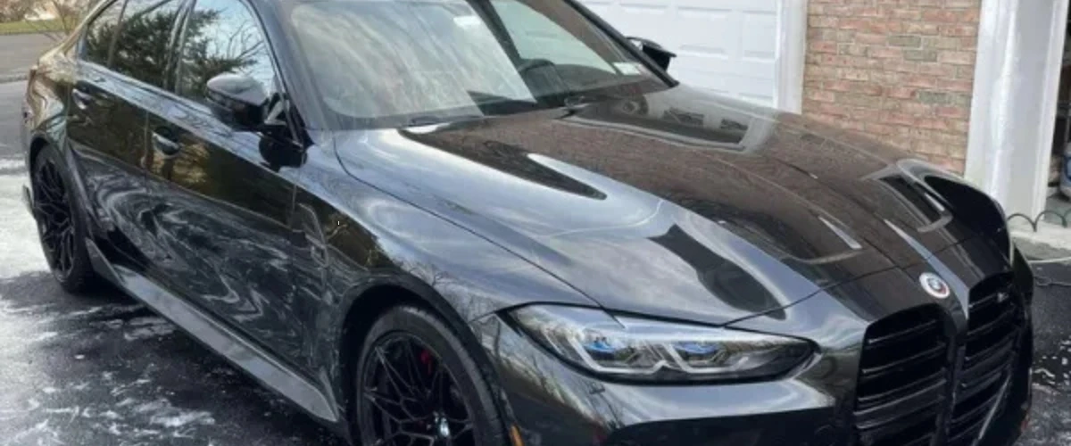 Black BMW M3 sedan with a glossy ceramic coating finish parked in a driveway after professional detailing. Black BMW M3 sedan with a glossy ceramic coating finish parked in a driveway after professional detailing.