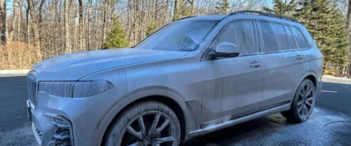 BMW SUV covered in white foam during an exterior car wash and detailing session.