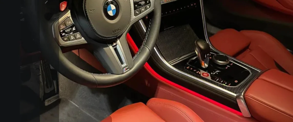 Close-up of BMW interior with red leather seats and detailed steering wheel during car interior cleaning.
