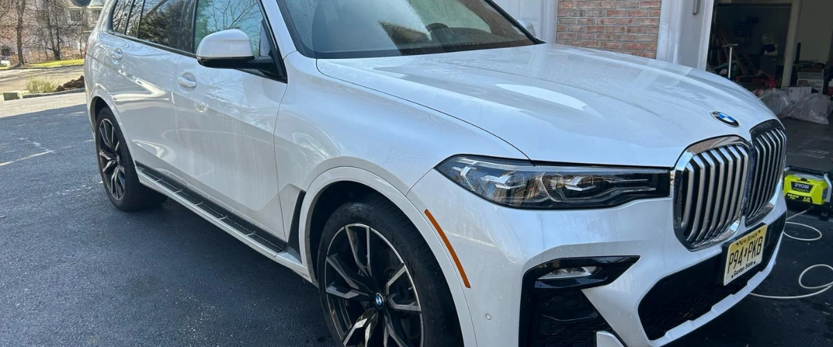 Clean white BMW SUV after full exterior detailing parked in driveway.