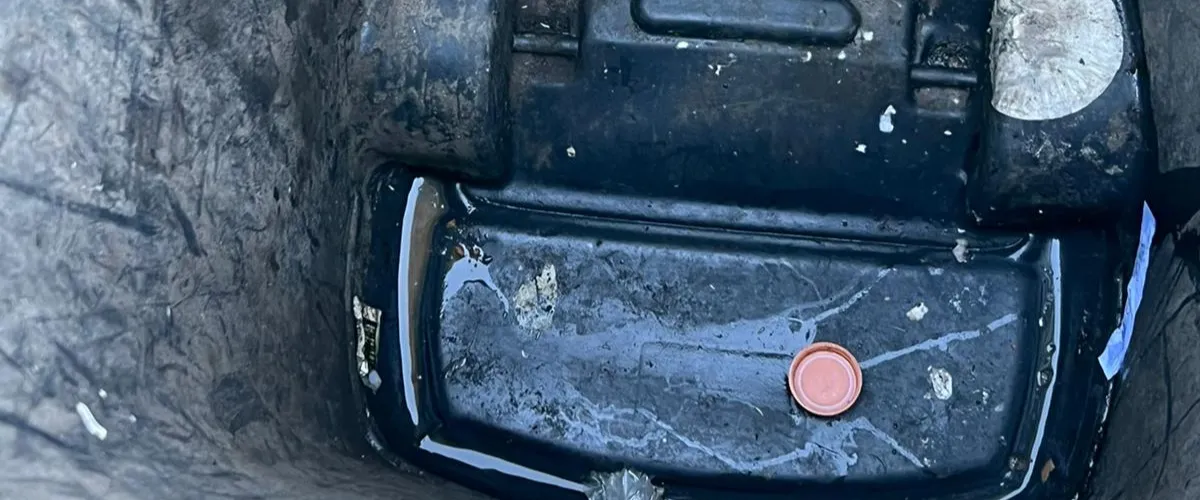 Dirty black trash bin with standing water and debris at the bottom