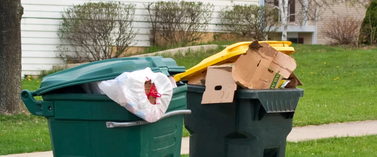 Overfilled trash bins with garbage bags and cardboard placed curbside Overfilled trash bins with garbage bags and cardboard placed curbside