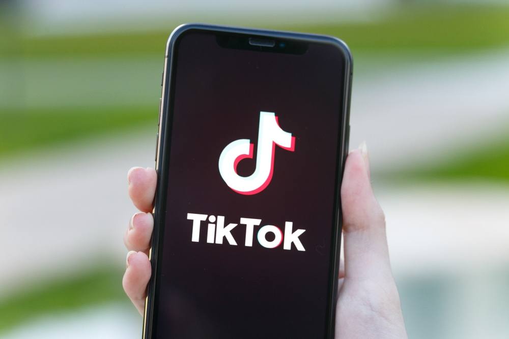 a hand holding a cellphone with the words TikTok and its logo on it