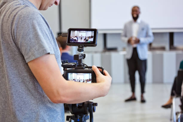 The display screens of the camera offer a mirrored view of the engagement, highlighting the symbiosis between technology and human interaction. 📹🗣🎤👥