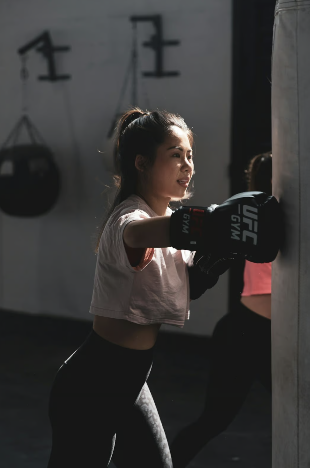 woman in pink t-shirt and black shorts holding black and white nike boxing gloves woman in pink t-shirt and black shorts holding black and white nike boxing gloves