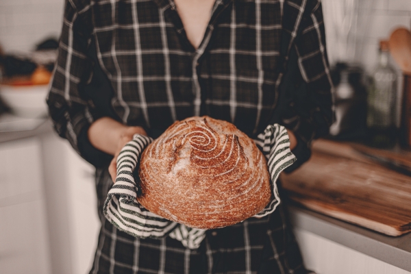 woman holding a fresh loaf of sourdough bread woman holding a fresh loaf of sourdough bread