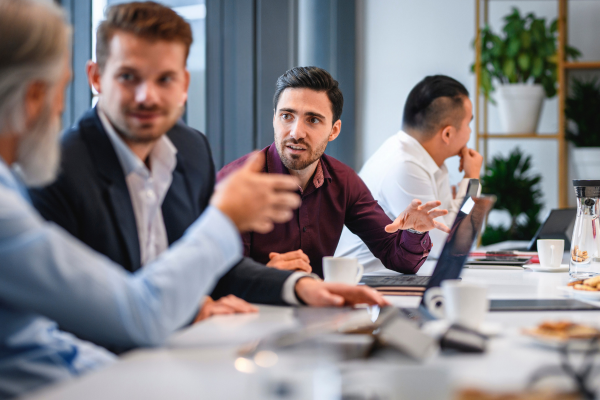 A group of business professionals in a meeting, struggling with outdated strategies, representing the cost of delaying restructuring A group of business professionals in a meeting, struggling with outdated strategies, representing the cost of delaying restructuring