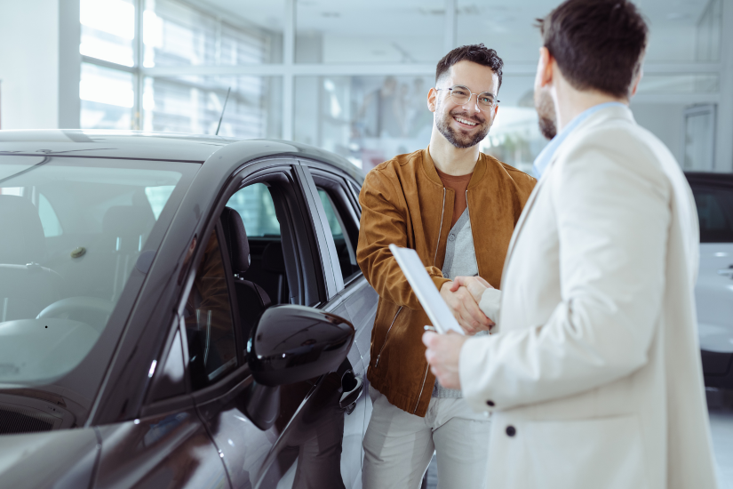 A happy car buyer shaking hands with a salesperson at a dealership, symbolizing a successful and positive car-buying experience. A happy car buyer shaking hands with a salesperson at a dealership, symbolizing a successful and positive car-buying experience.
