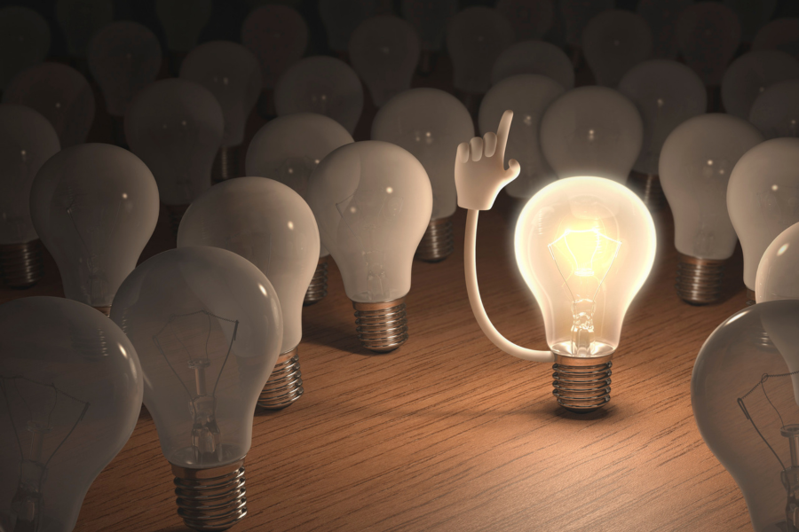 A glowing lightbulb with a raised hand among dim bulbs, symbolizing visionary thinking, mental clarity, and leadership distinction. A glowing lightbulb with a raised hand among dim bulbs, symbolizing visionary thinking, mental clarity, and leadership distinction.