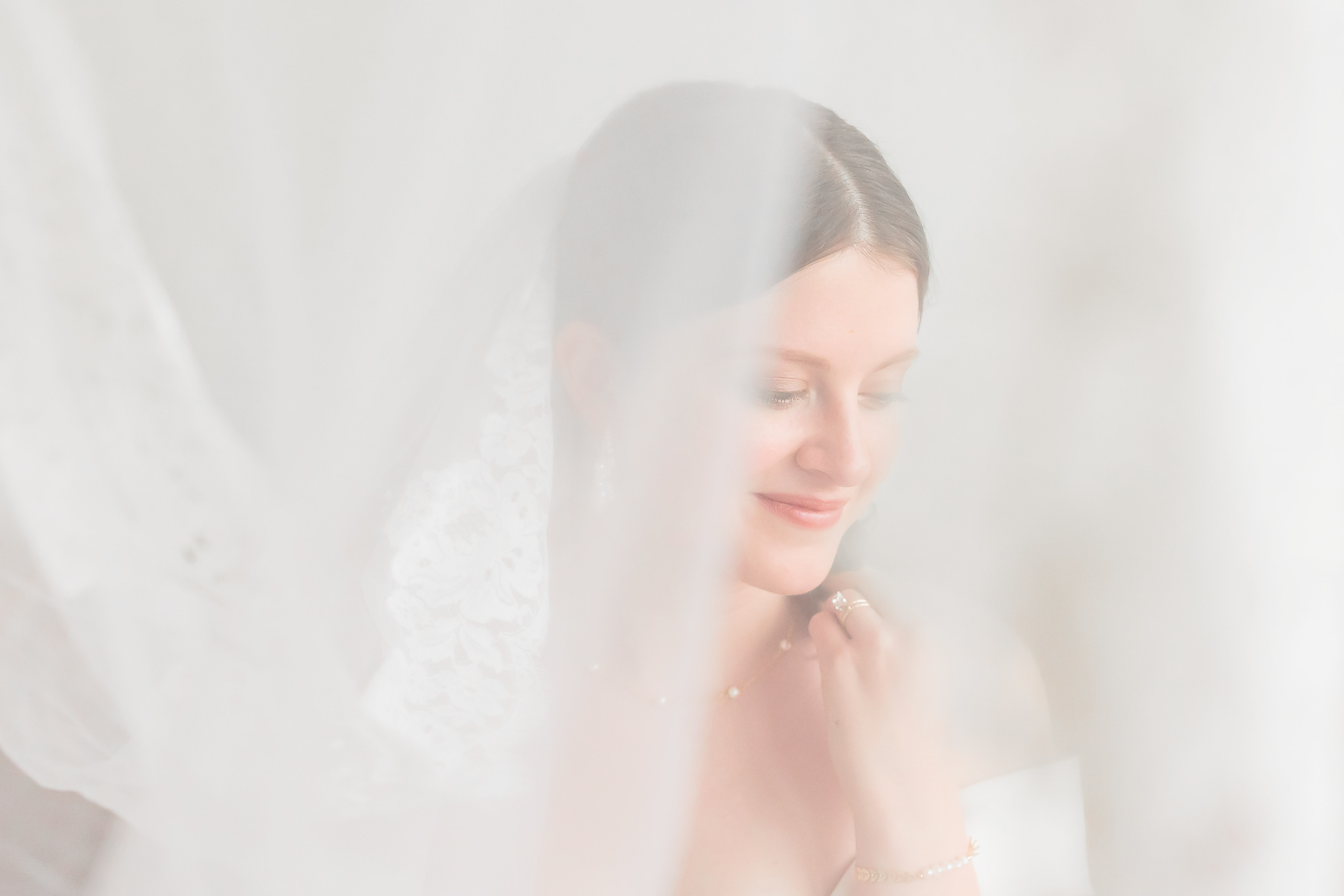 Bride with a delicate veil in soft light, captured by Double Knot Photography, highlighting an ethereal bridal portrait.