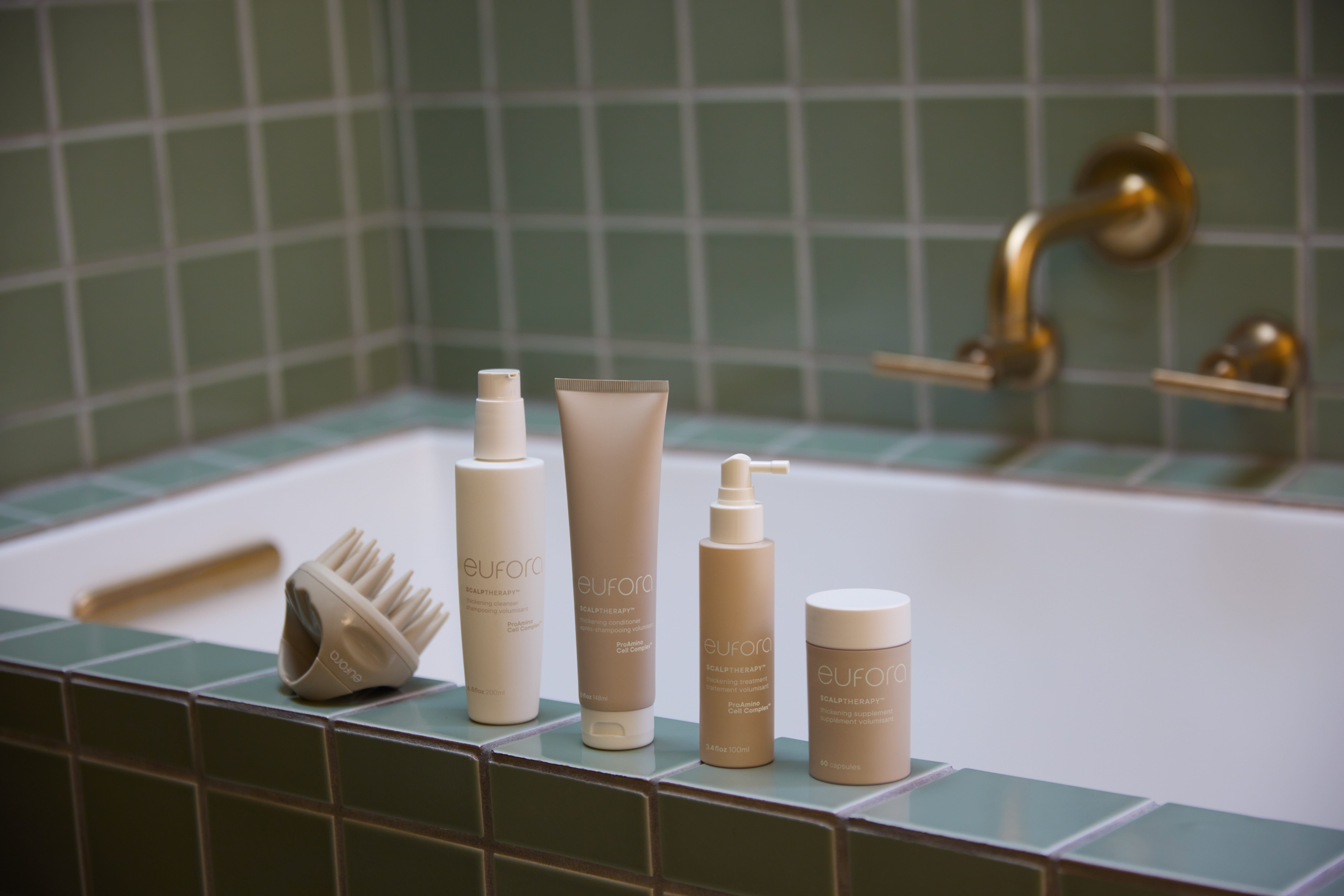 Eufora international Thickening Regimen Thickening Cleanser, Thickening Hair Conditioner, Thickening Scalp Treatment, and Thickening supplements on a green tiled bathtub. 
