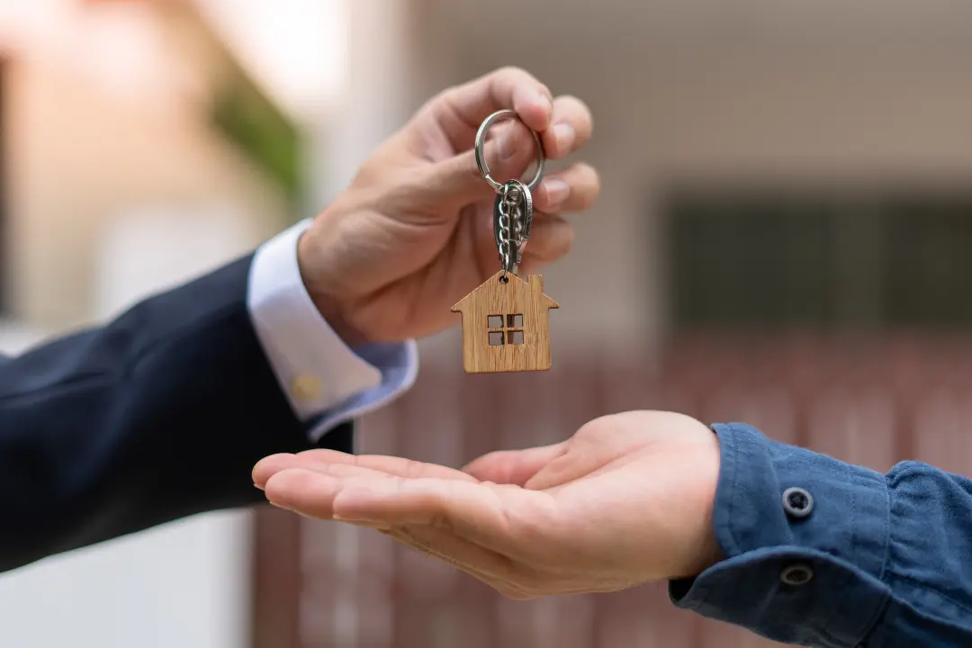 Realtor handing keys to buyer for new home.