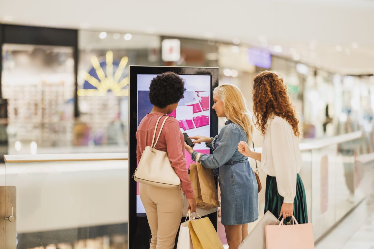 women interacting with digital signage kiosk