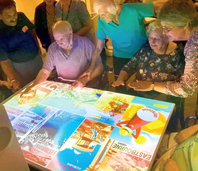 memory care residents playing interactive projection game on table memory care residents playing interactive projection game on table