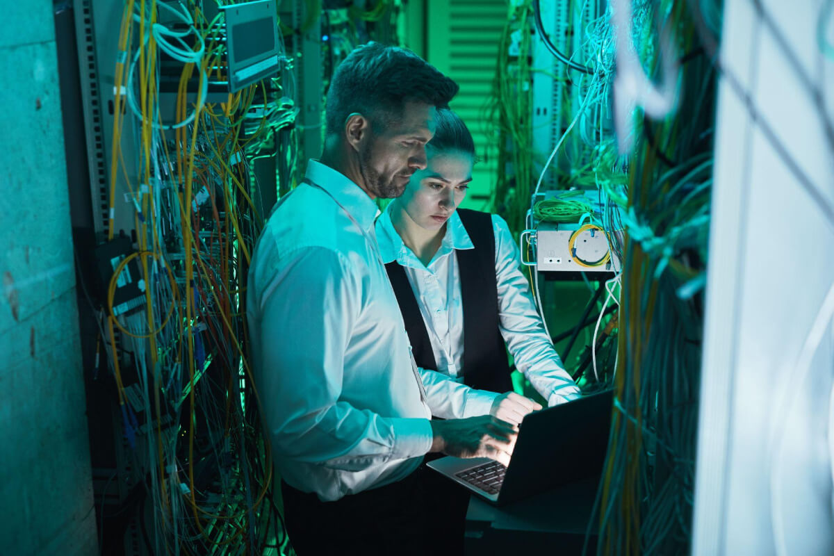 IT specialist working with member of in-house team in server room during cybersecurity incident IT specialist working with member of in-house team in server room during cybersecurity incident