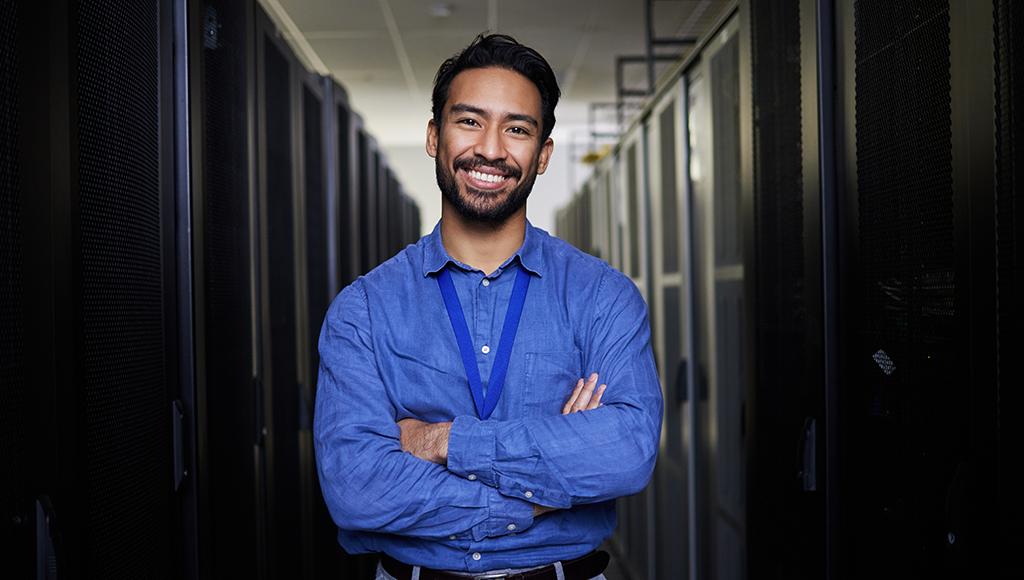 An IT outsourcing expert stands smiling in a server room, ready to help. An IT outsourcing expert stands smiling in a server room, ready to help.