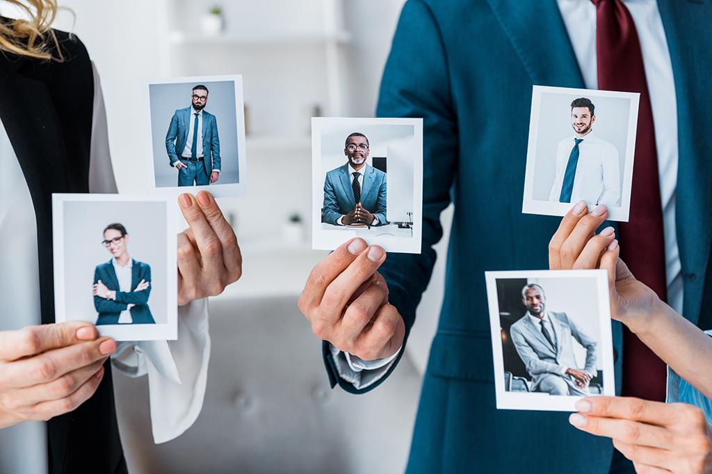 Recruiters at a manufacturing plant hold up images of potential employees. Recruiters at a manufacturing plant hold up images of potential employees.