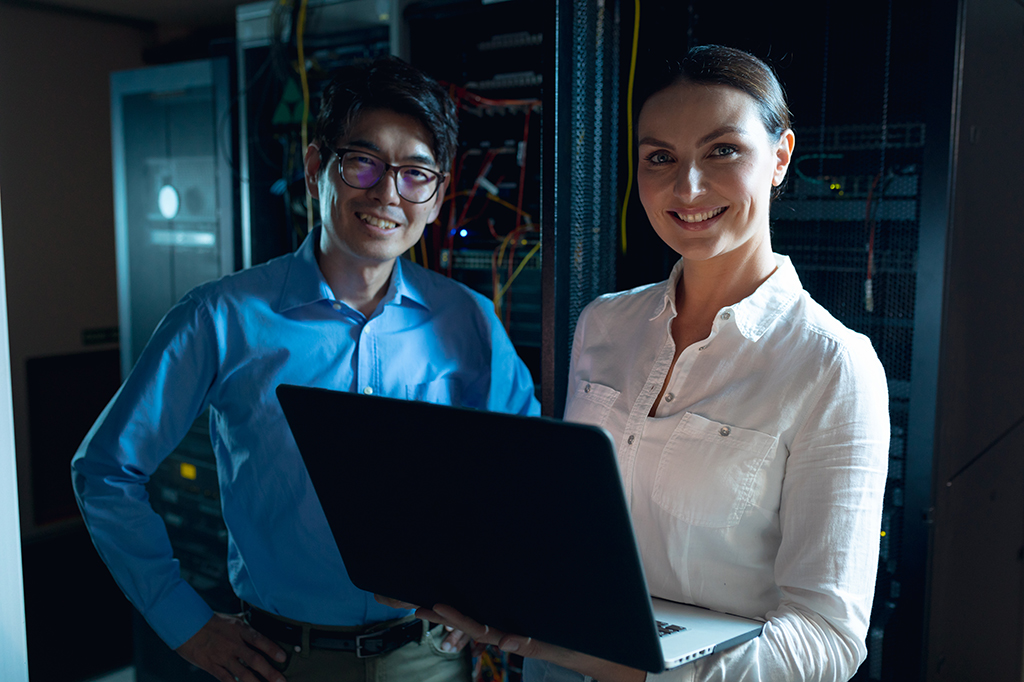 Two IT experts smiling by a server farm. Two IT experts smiling by a server farm.