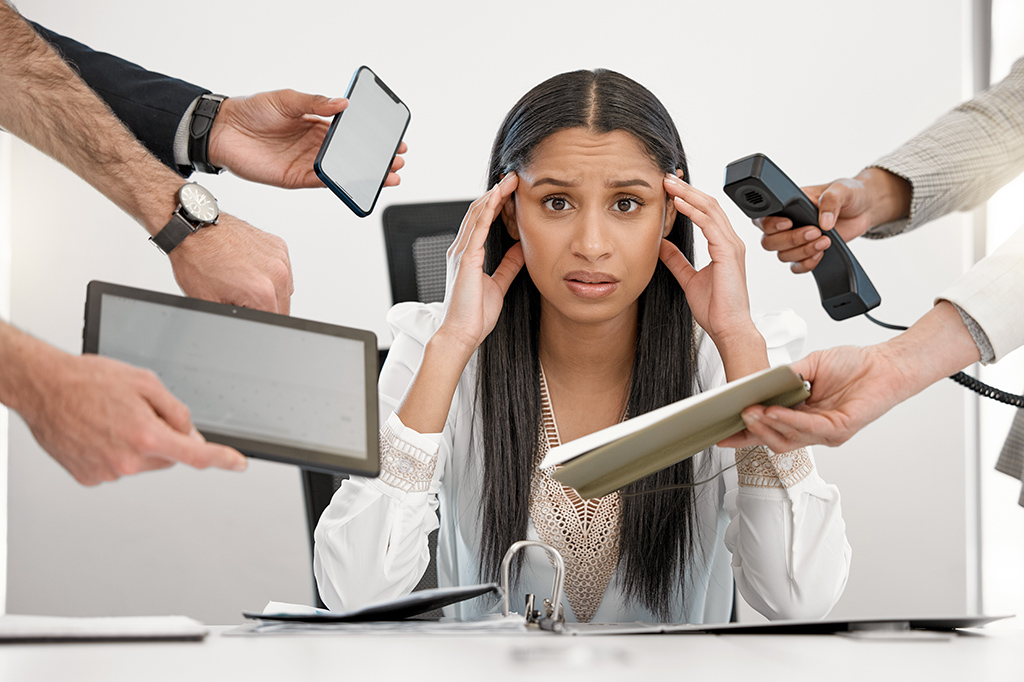 A stressed woman burdened by too many tech tools. A stressed woman burdened by too many tech tools.