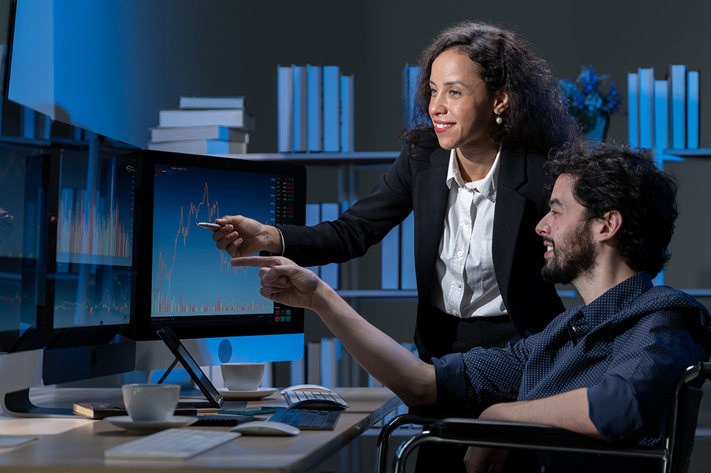 An IT support specialist shows someone how to navigate a report An IT support specialist shows someone how to navigate a report