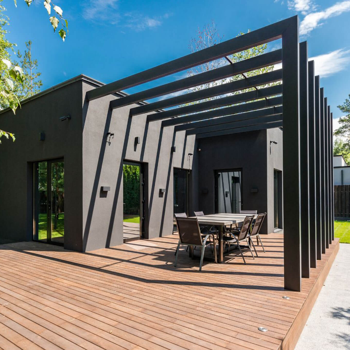 Modern custom pergola and patio cover in Garland TX with open slat design, outdoor dining area, and raised wood deck