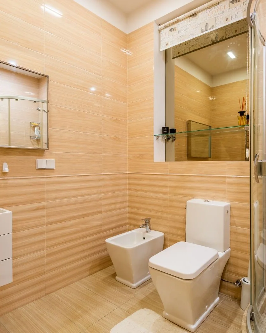 Modern bathroom remodel in Allen, TX with glass shower, wall-mounted fixtures, and updated tile design.