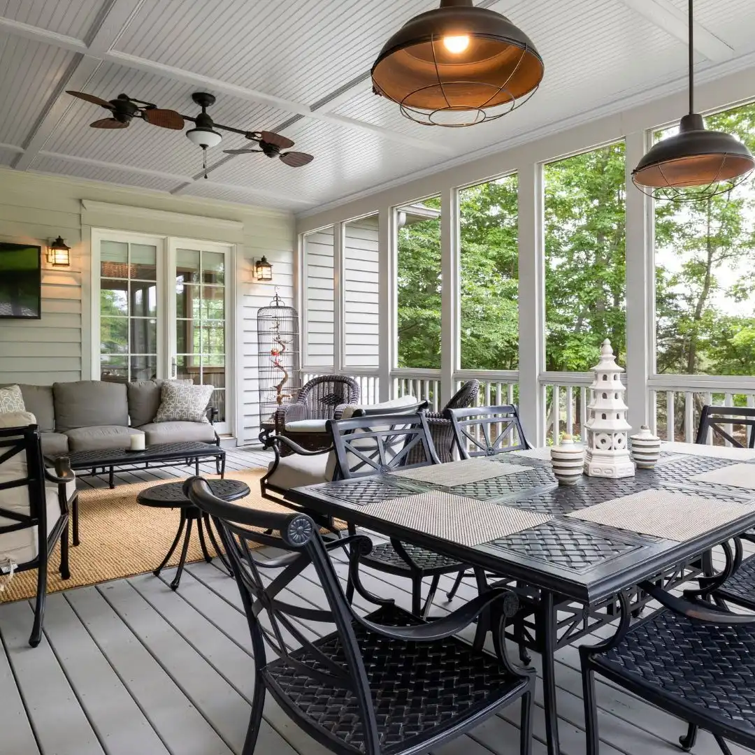 Screened patio cover in Wylie, TX with outdoor dining table, ceiling fans, and pendant lighting.