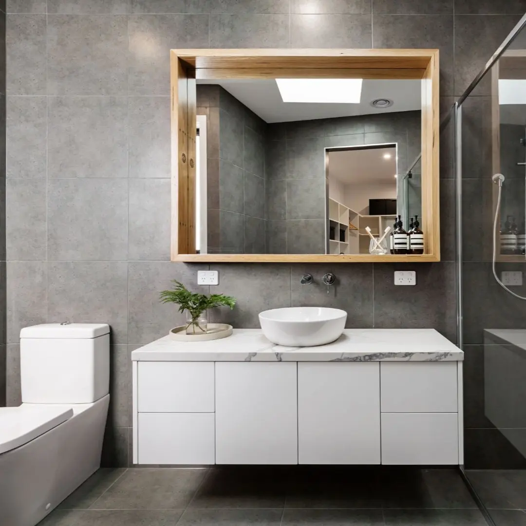 Modern bathroom remodel in Rowlett TX with floating white vanity, vessel sink, large framed mirror, glass shower, and gray tile by Texas Woodpeckers