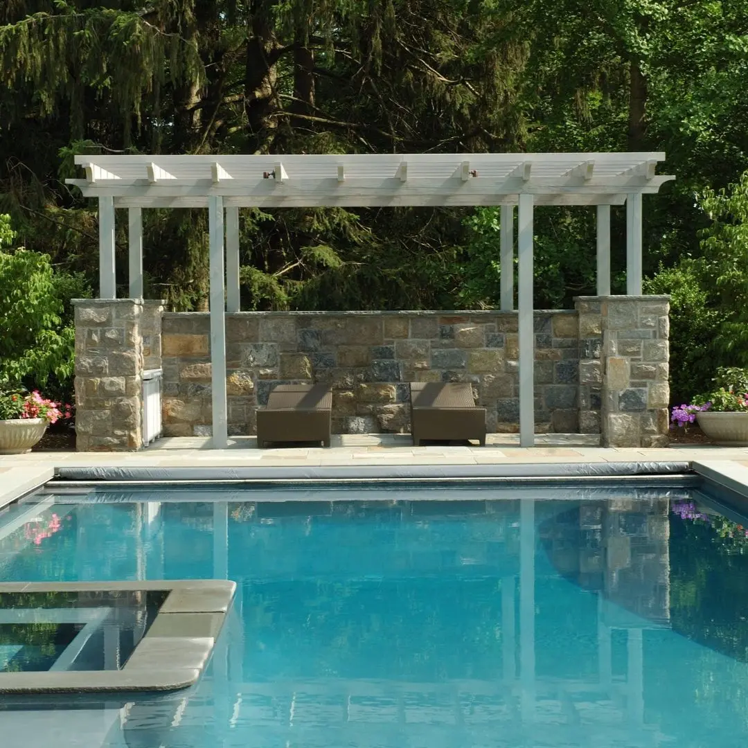 Custom pergola with stone privacy wall beside a backyard pool in Rowlett, TX