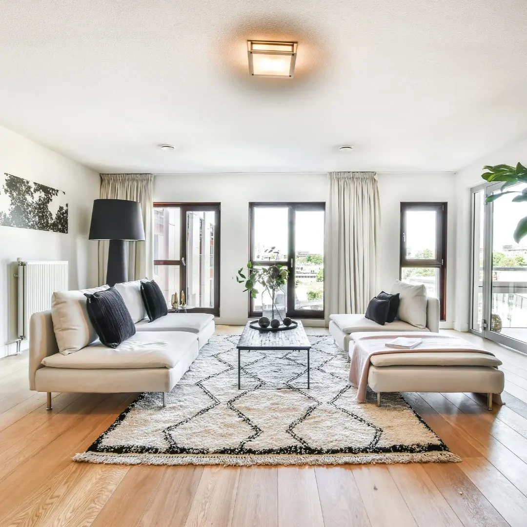 Modern living room with wide plank wood flooring, neutral sofas, large windows, and balcony doors in Rowlett TX whole-home remodel