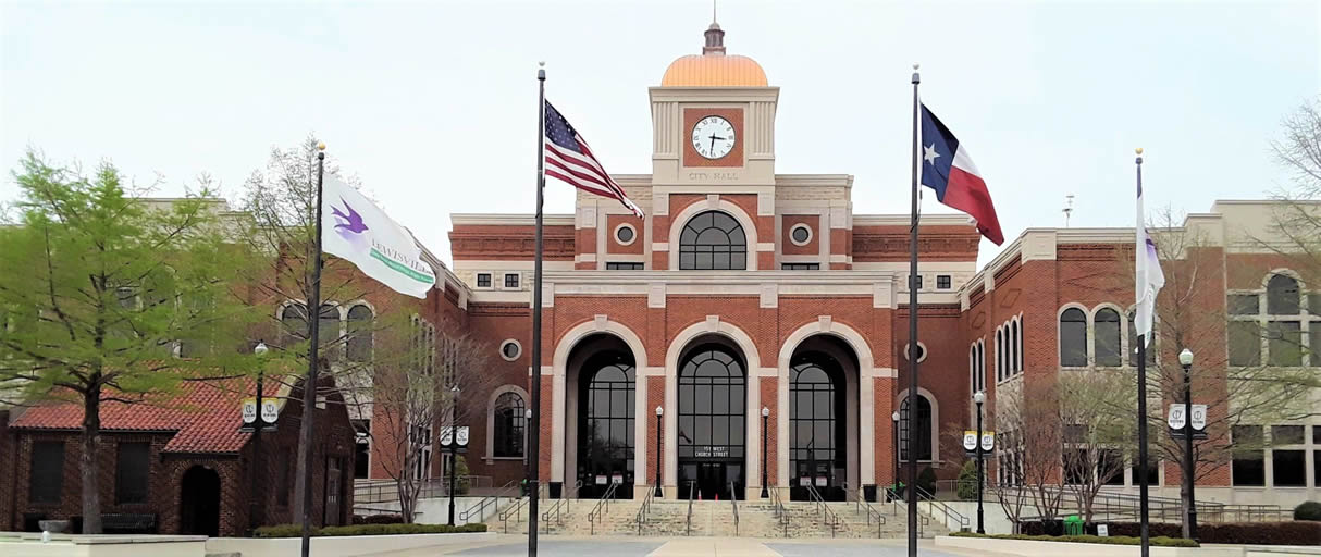 Front view of Lewisville City Hall in Texas with American and Texas flags, representing the city’s community and civic center.