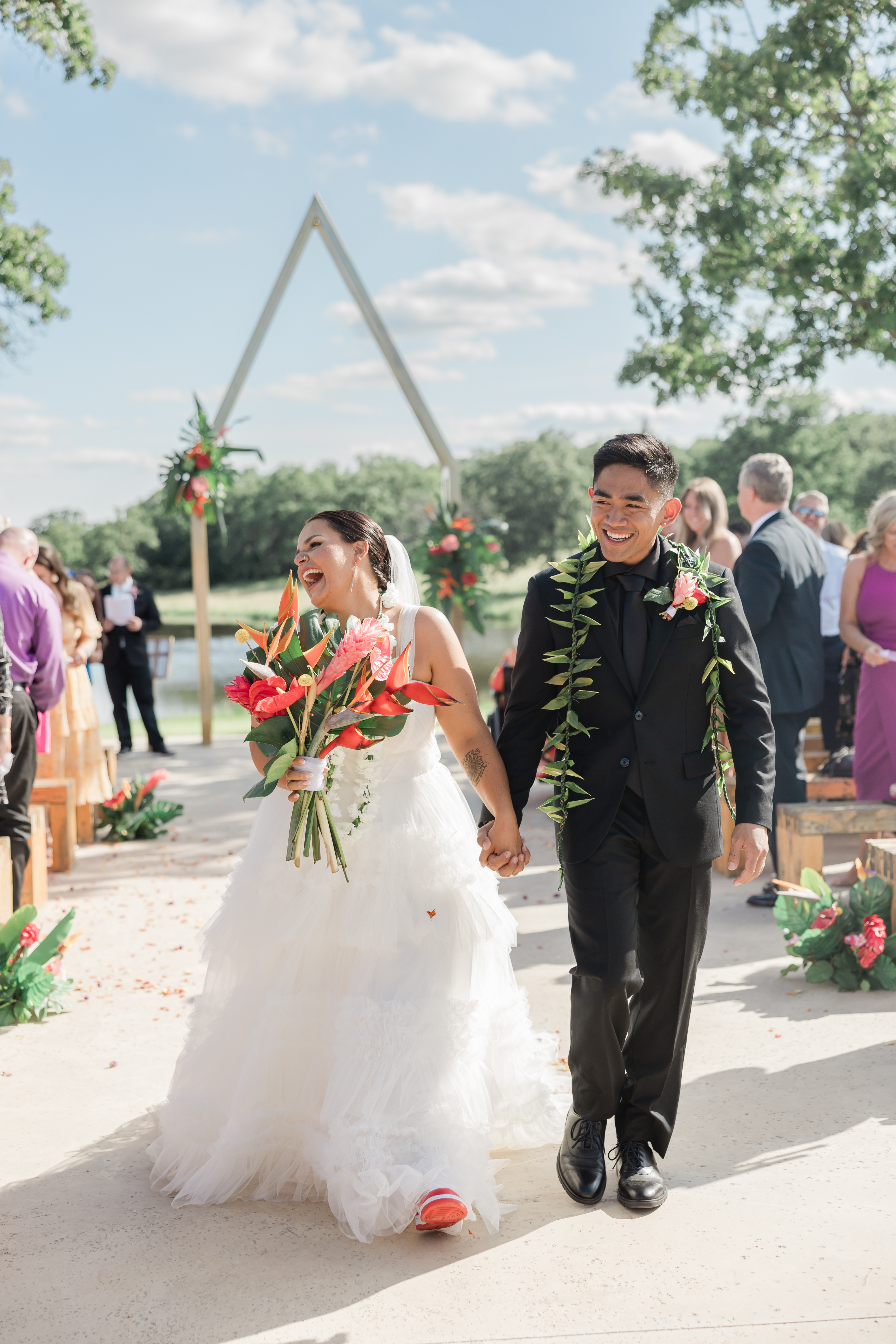 Image of bride and groom laughing hand in hand as they walk back down the aisle