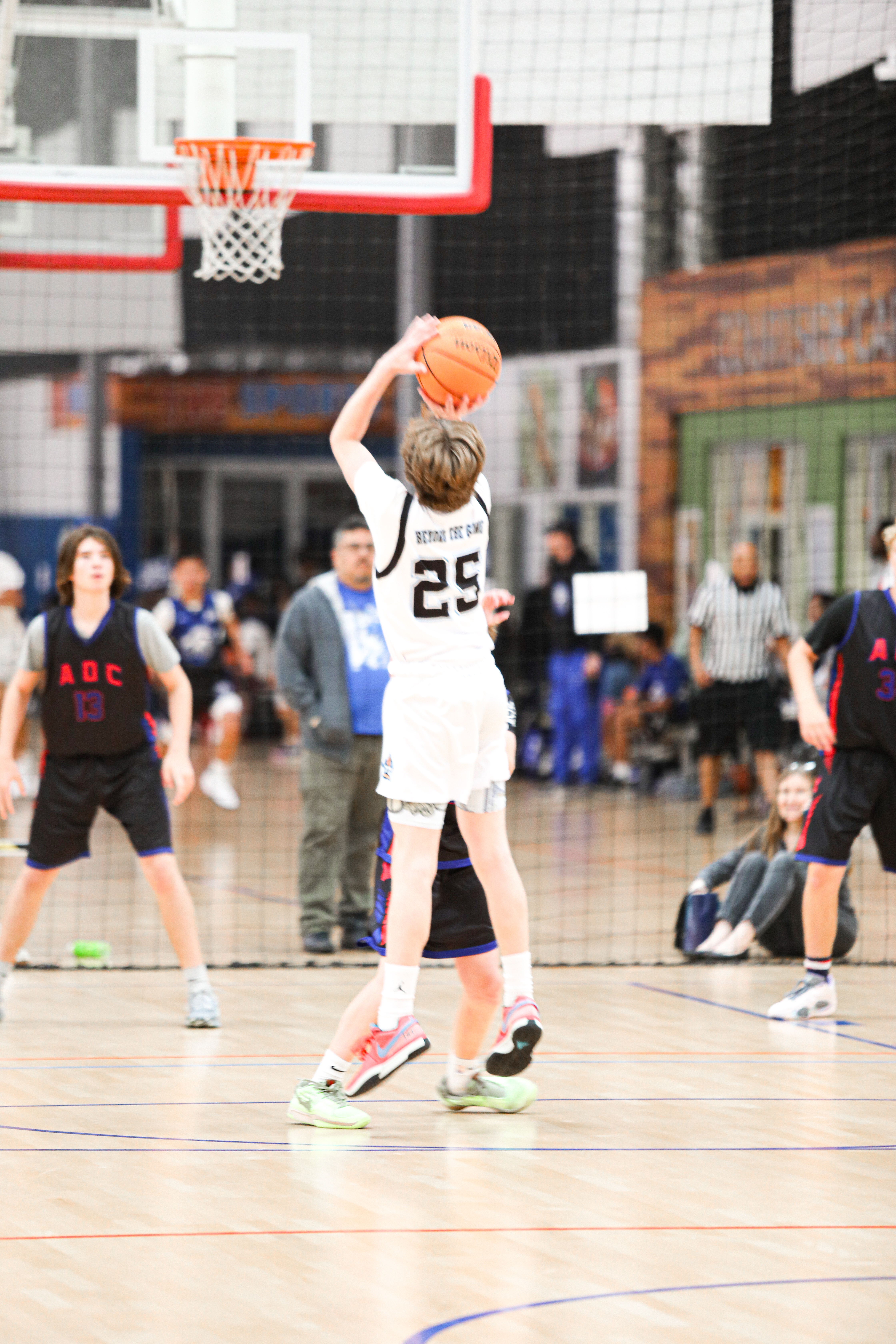 Young boy shooting a basketball in an indoor basketball court during a summer baksetball camp