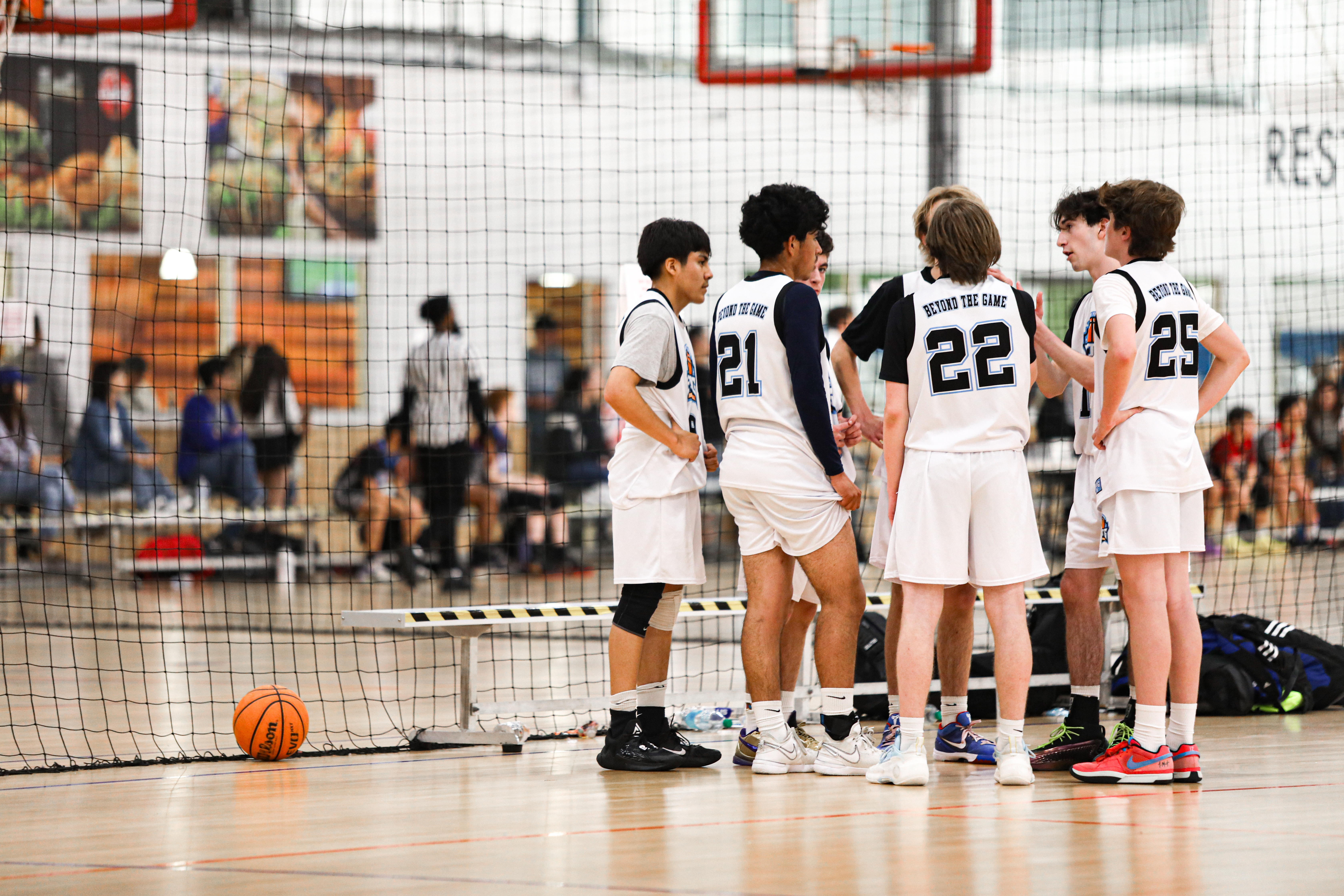 Team huddled together during youth summer basketball camp in an indoor court 