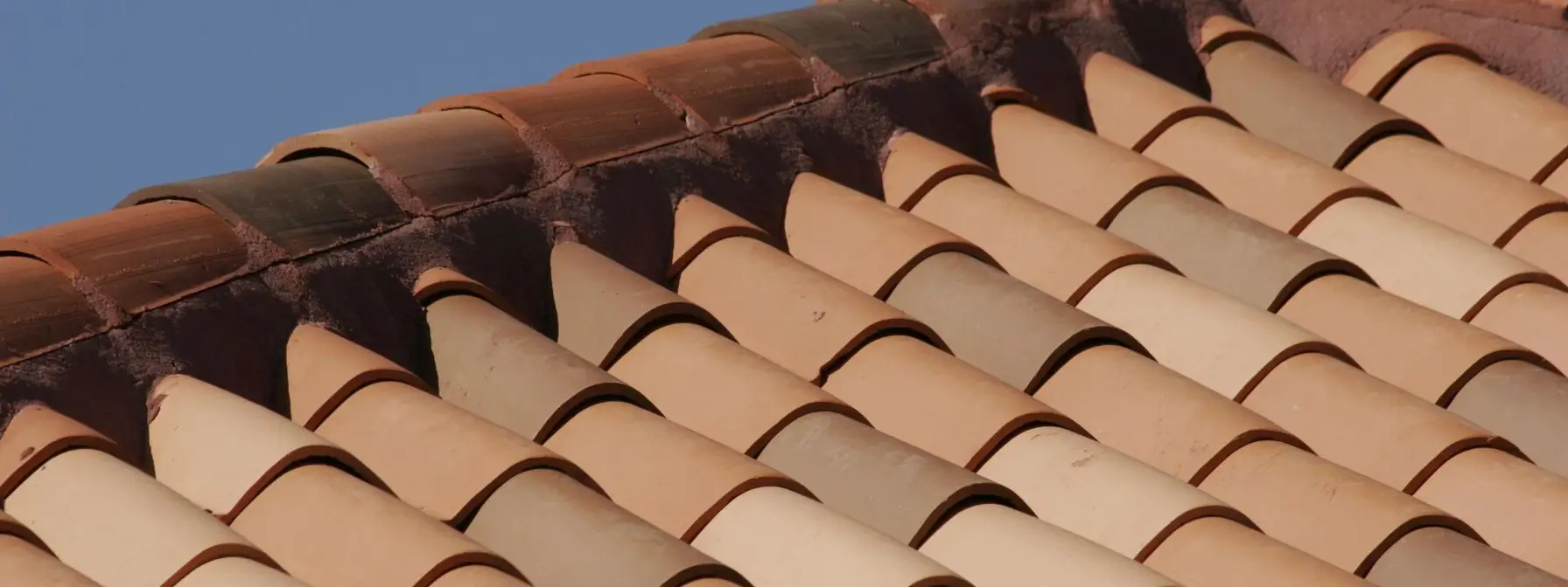 Close-up view of clay roof tiles under direct sunlight, highlighting how heat and UV radiation can cause wear and discoloration—common summer roofing risks in Ashland, KY. Close-up view of clay roof tiles under direct sunlight, highlighting how heat and UV radiation can cause wear and discoloration—common summer roofing risks in Ashland, KY.