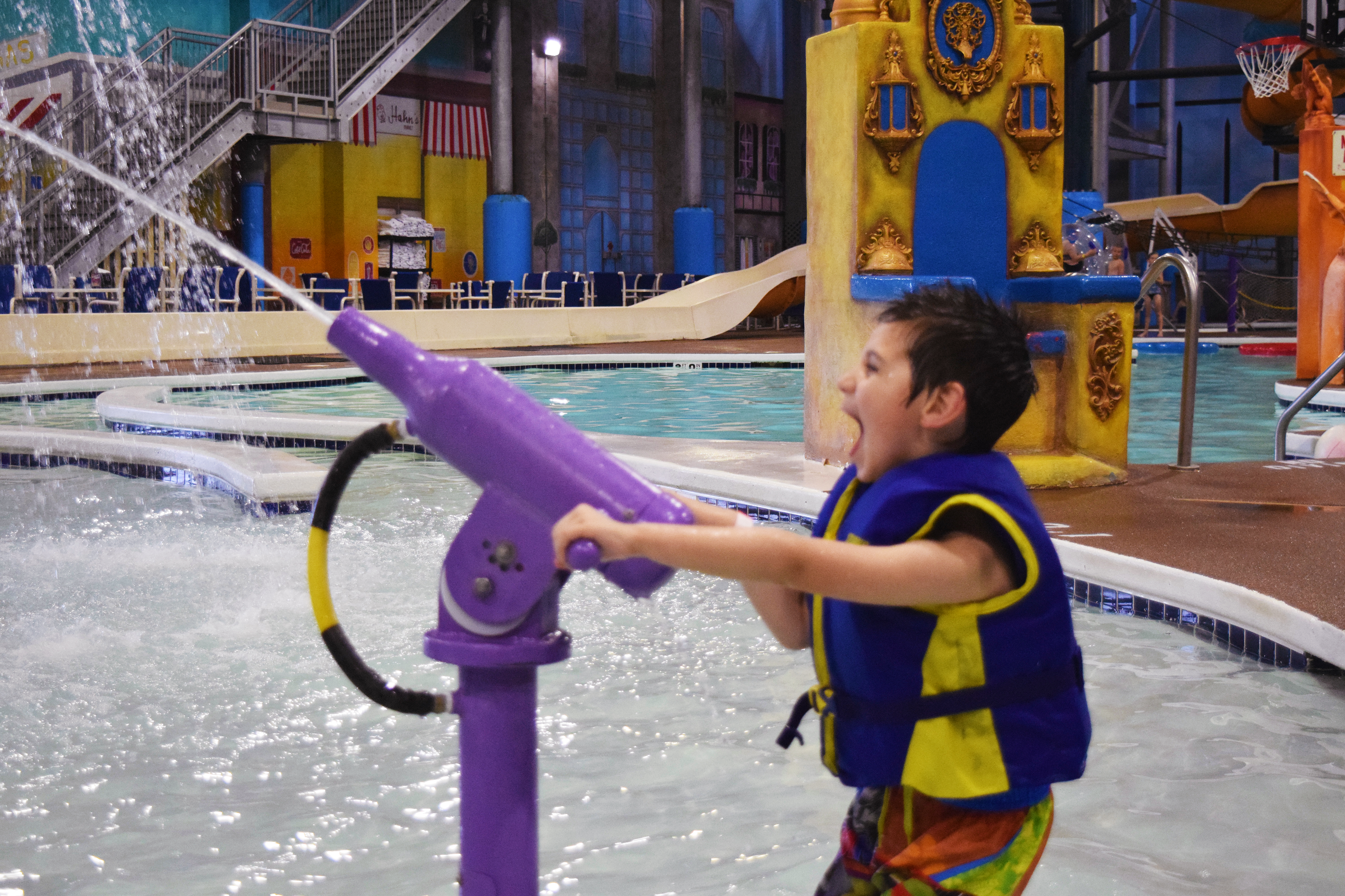 A kid playing with a water gun at the indoor aquatic playground in Chaos Water Park