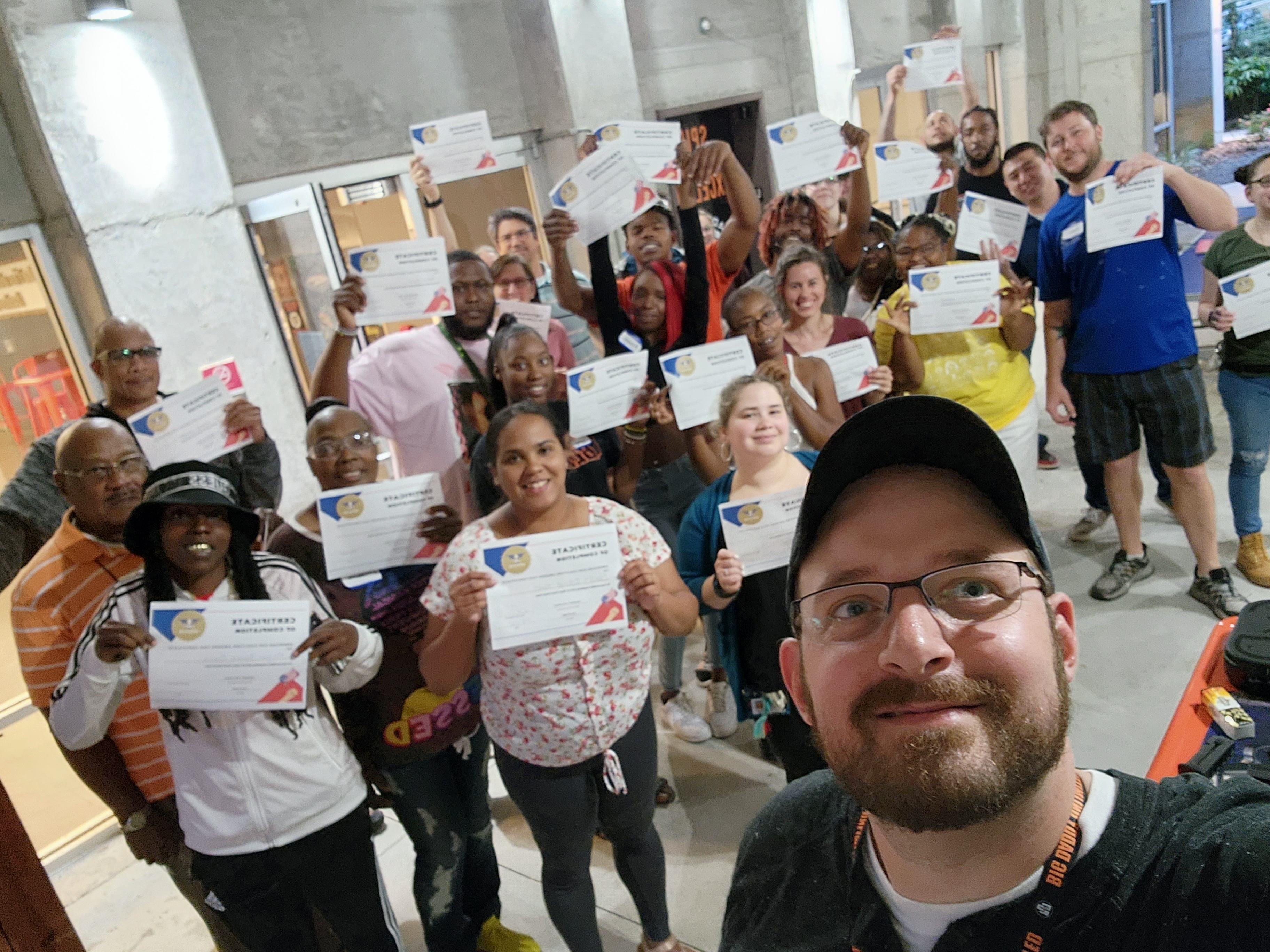 Graduates of a firearms training course posing with certificates and their instructor.