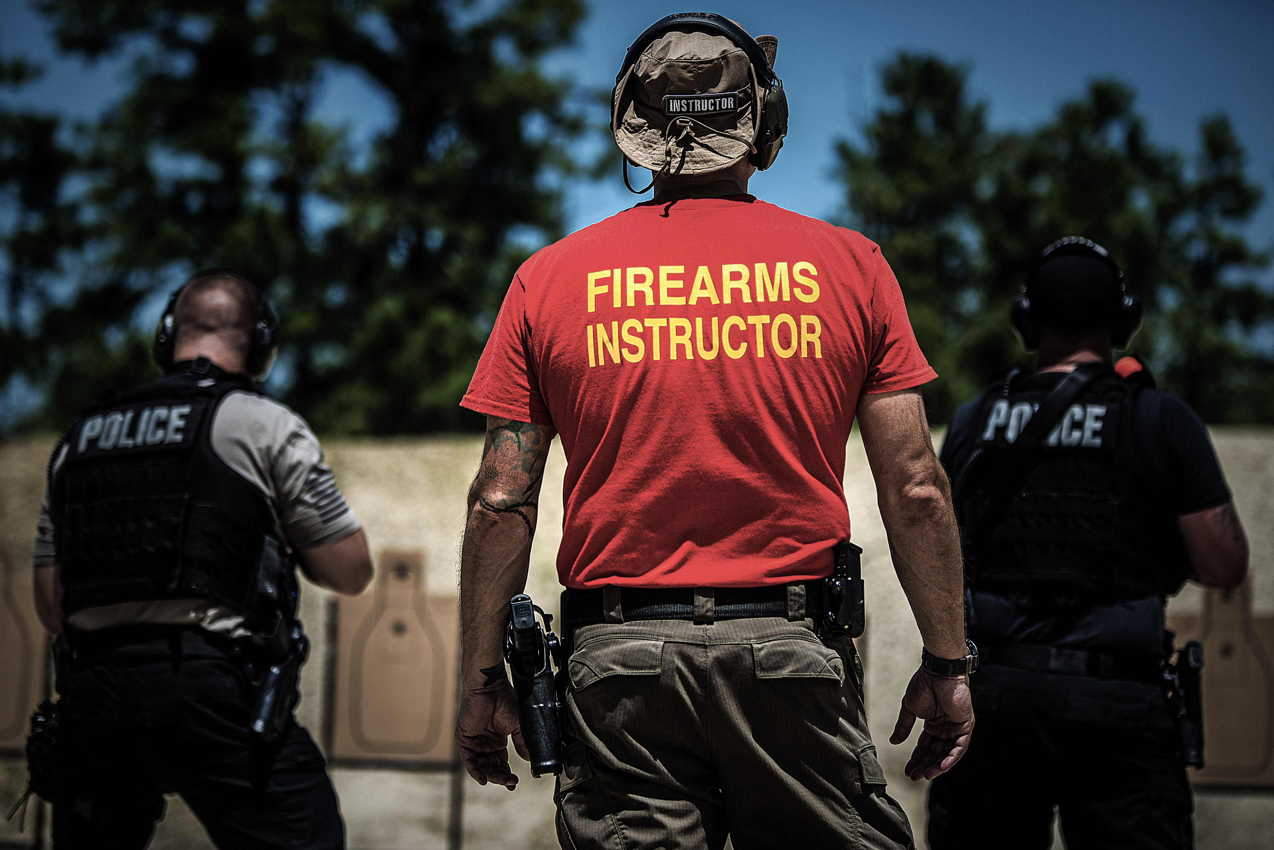 Firearms instructor giving a hands-on shooting lesson to students at a gun range.