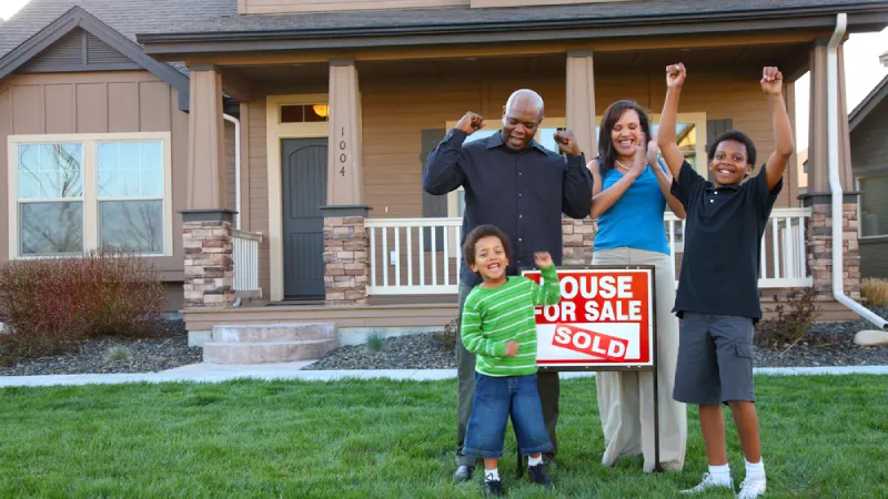 Family celebrating in front of their newly purchased house