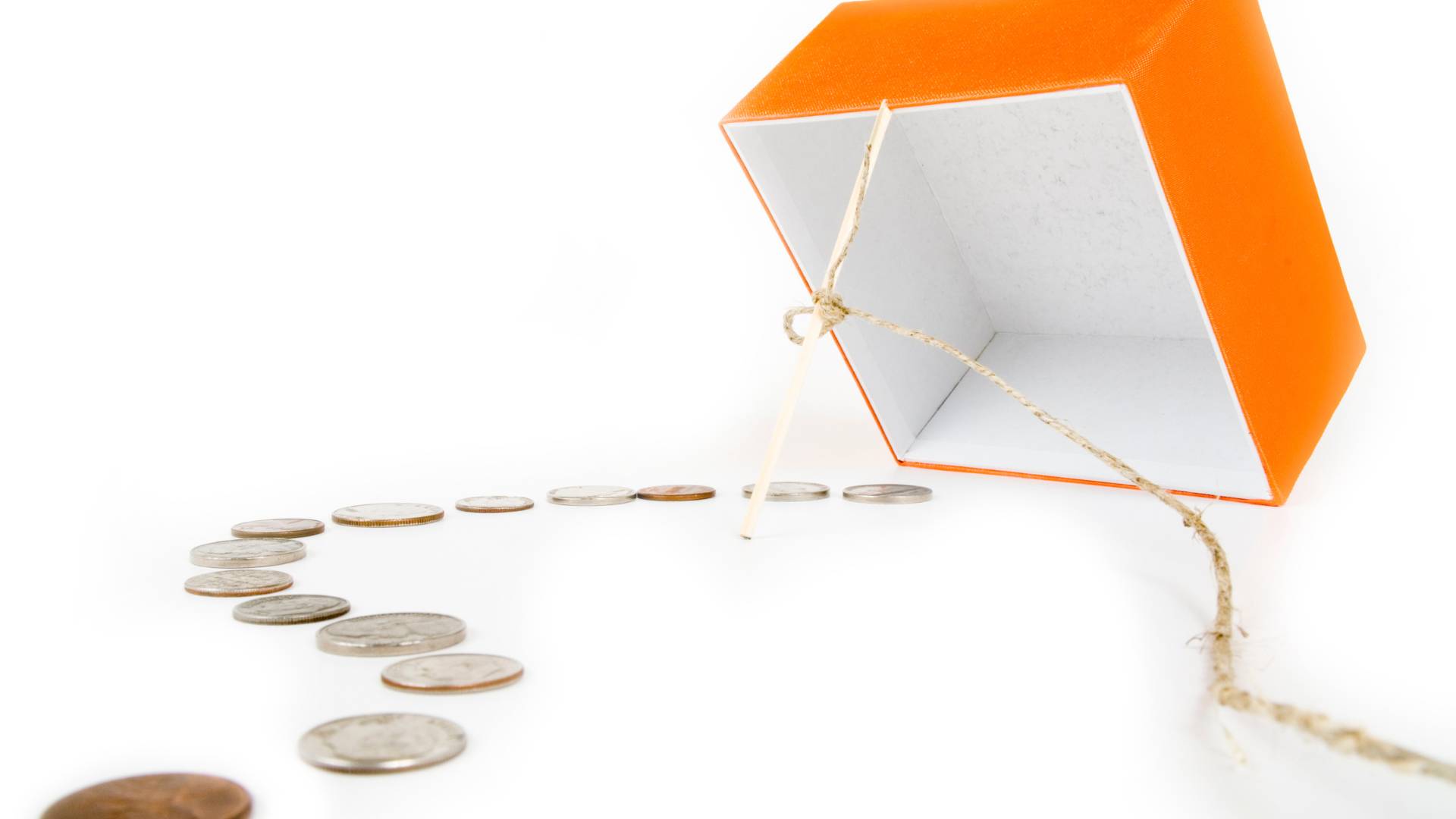 a homemade trap with a box a stick and some coins lying on the floor to lure their targeted pray